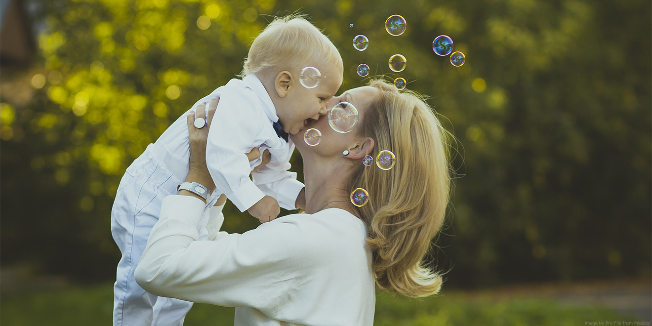 Mutter küsst ihr lachendes Baby. Zum Mutter- und Vatertag werden viele Geschenke gemacht. Lachen und Liebe schenken sind die Schönsten.
