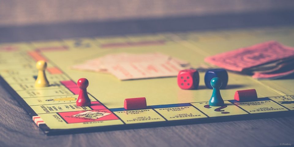 Bettspiel Monopoly mit Spielfiguren und Würfel