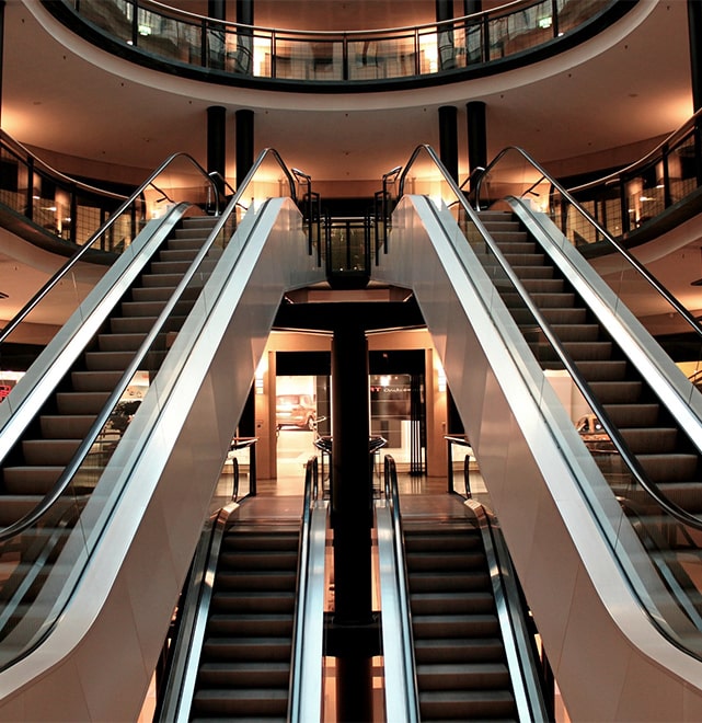 Einkaufszentrum mit Rolltreppen und vielen Geschäften.