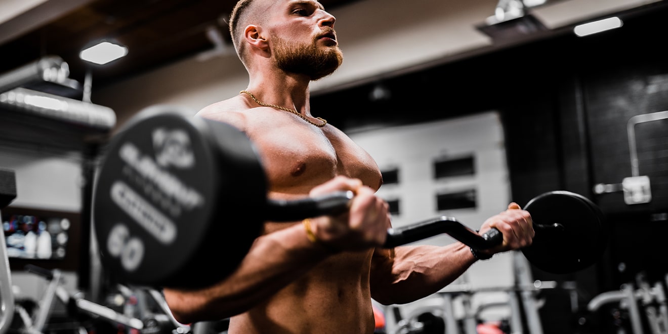 Mann trainiert im Fitnessstudio. Zum Aufbau von Muskeln ist der Eiweißbedarf höher. 